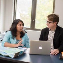 Student sitting with staff at a desk talking