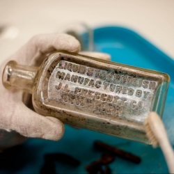 Old, small, glass bottle being cleaned with toothbrush