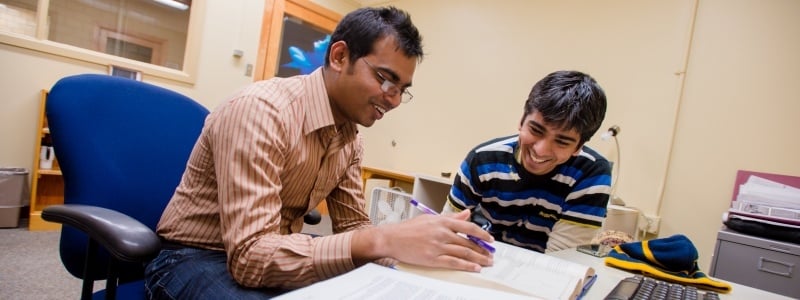 Graduate students looking over notes while sitting in a meeting room.