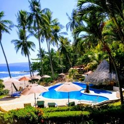 Beach with a large pool and umbrellas.