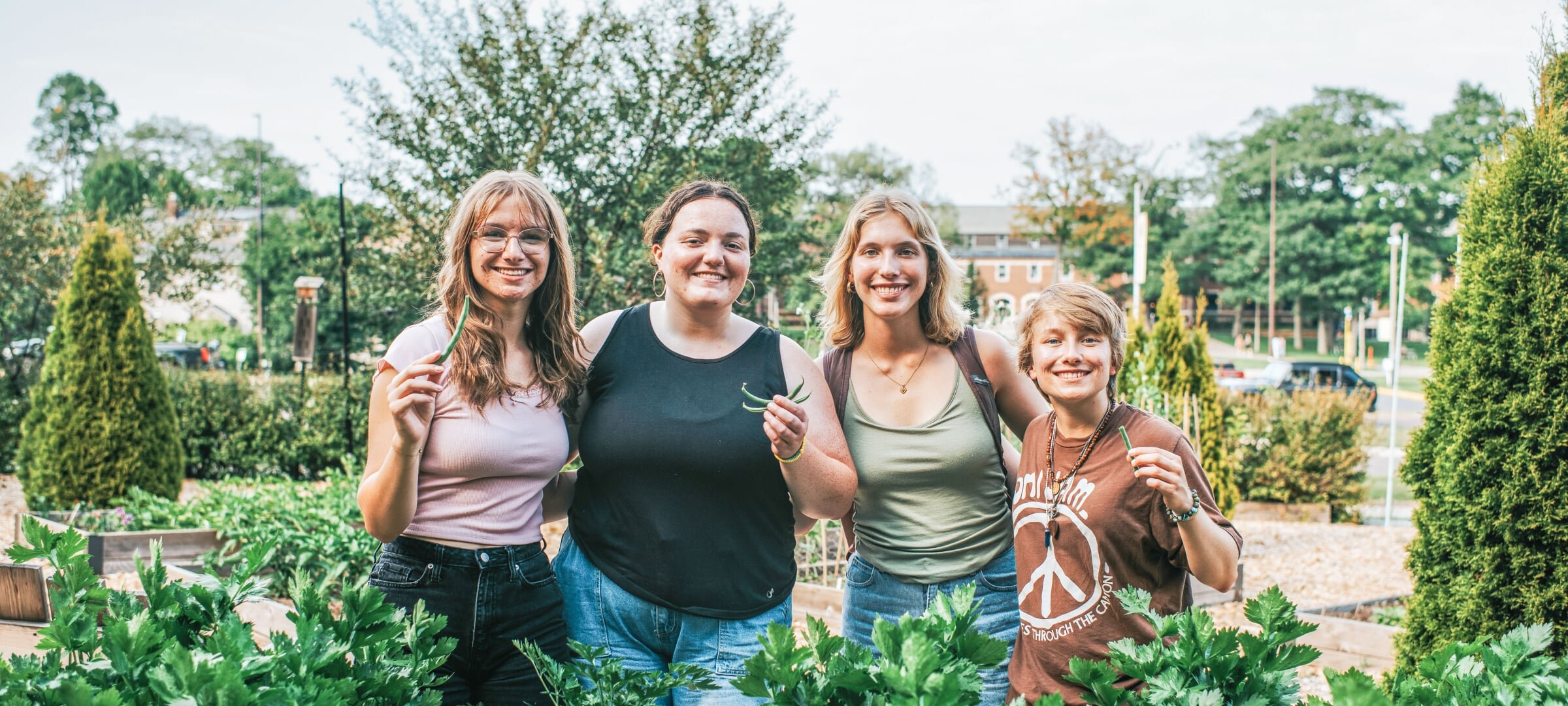 Four women students display harvest from their community garden.