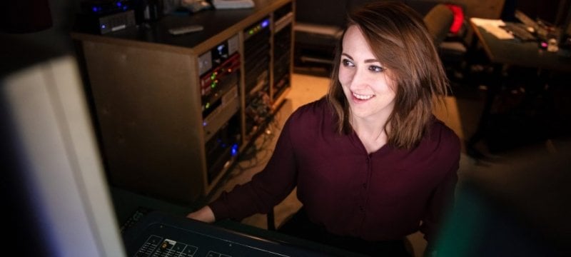 Sarah Calvert sitting at a sound mixing board.