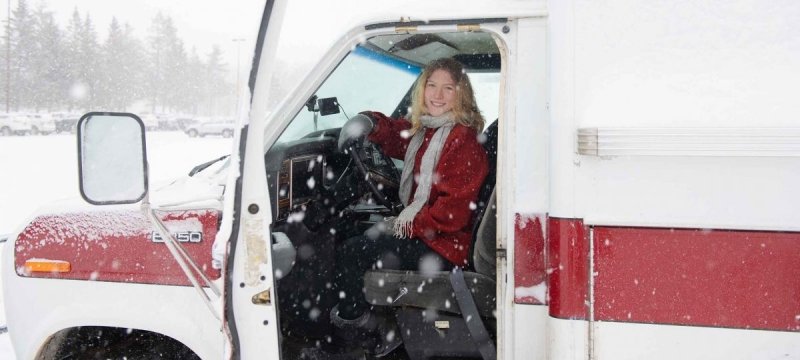 Sydney Skalski sitting in the driver's seat of her ambulance turned tiny home.