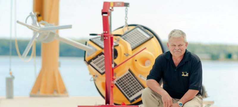 Guy Meadows kneeling near a buoy out of the water.