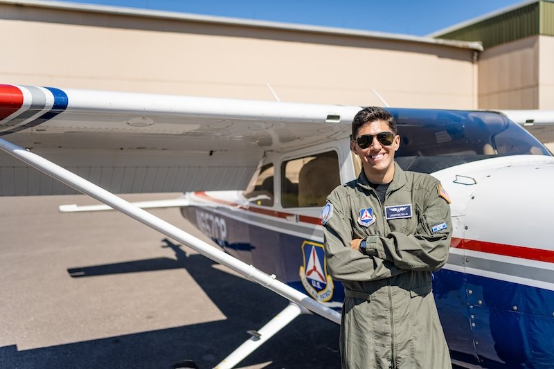 A young pilot in his flight suit stands by his plane at Houghton County memorial Airport. He is a Michigan Tech Air Force ROTC member, too.