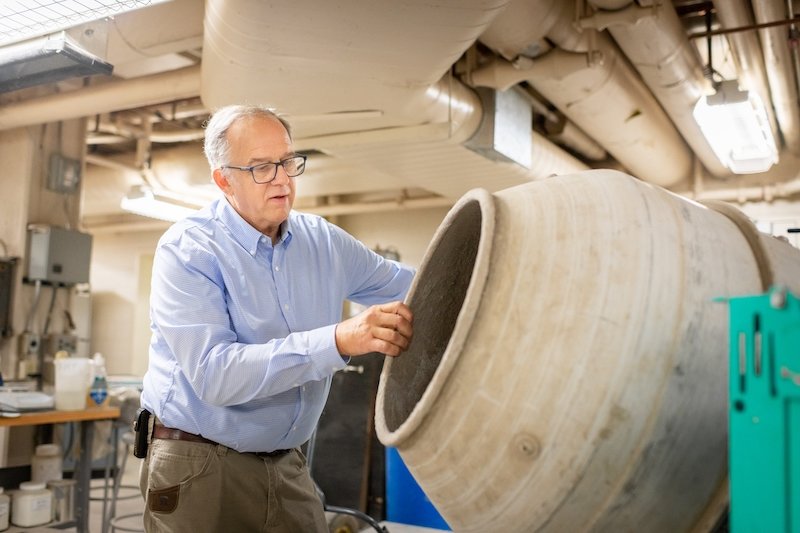 A man stands in a lab with concrete poured, he is an industry leader sharing his Michigan Tech story