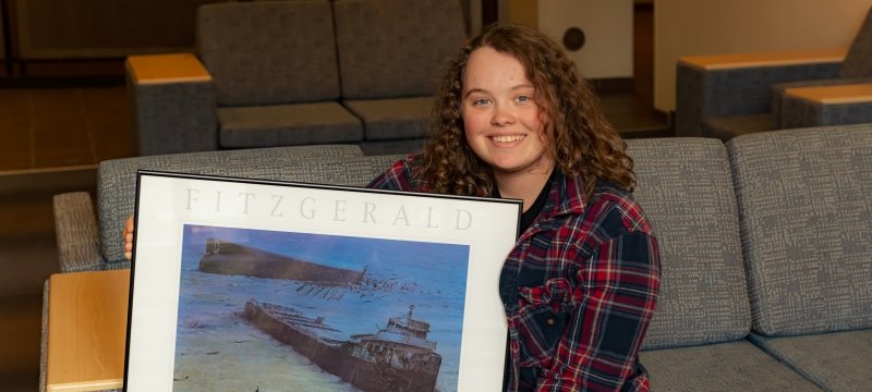 A first-year Tech student with a fascination for shipwrecks holds a print of the Edmund Fitzgerald