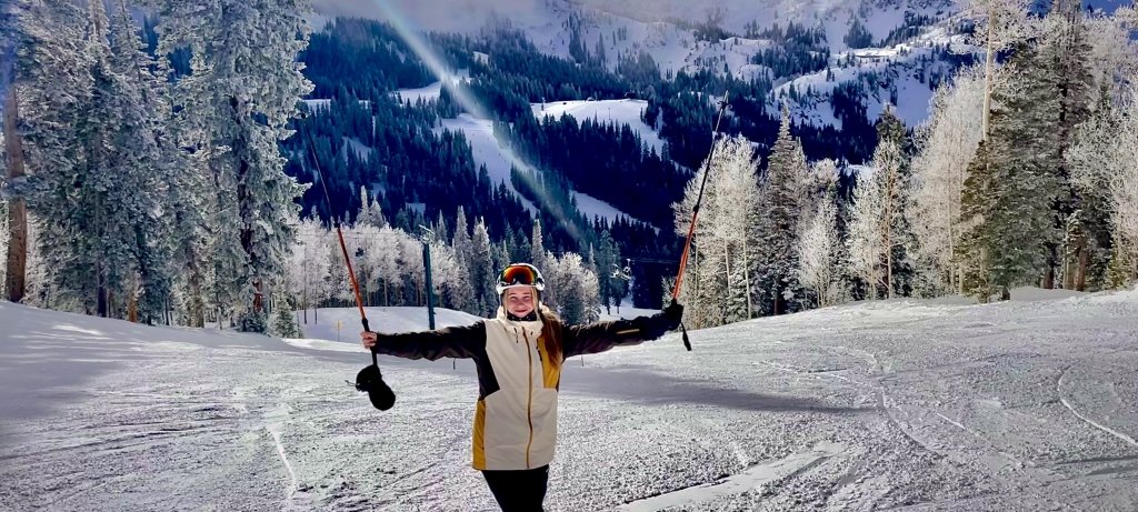 A young woman holds up her ski poles on a Utah Mountain; she's a third generation Michigan Tech Husky and new MTU soccer team member.