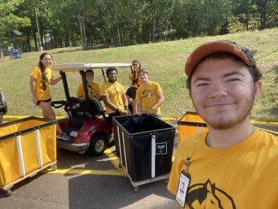 A group of student leaders at Tech with the 2023 student commencement speaker for undergrads in the foreground outside wearing Husky t-shirts.