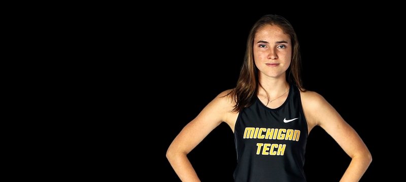 A runner in a Michigan Tech Jersey stands with hands on her hips. She just set a world record for crutch-running.