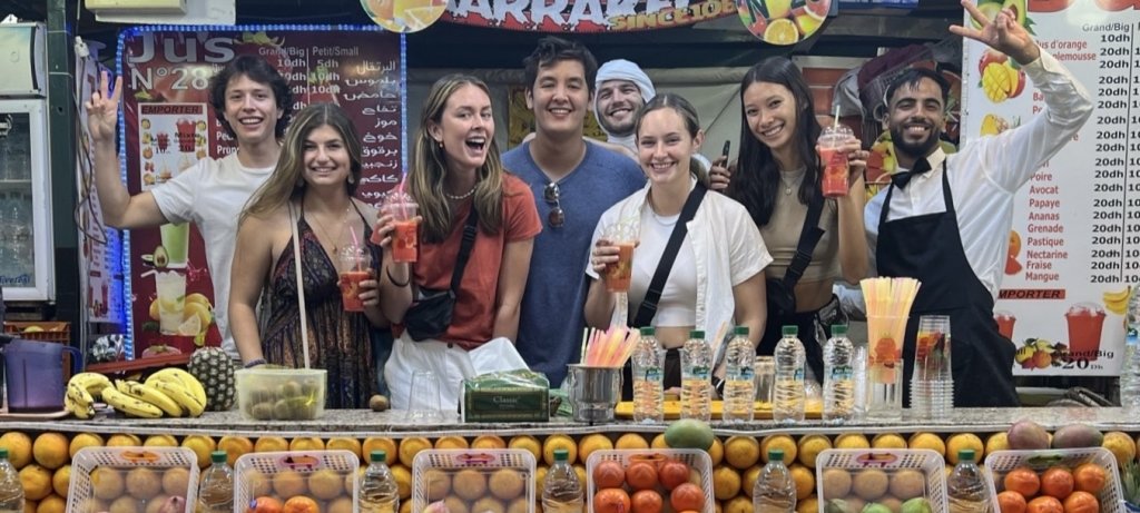 Eight young people at a smoothie stand while studying abroad, including a Michigan Tech Husky, Sophie Mehl, second from left