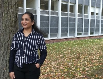 A visiting Fulbright scholar enjoys fall color season near Fisher Hall outside on the Michigan Tech campus where she is studying for six months.