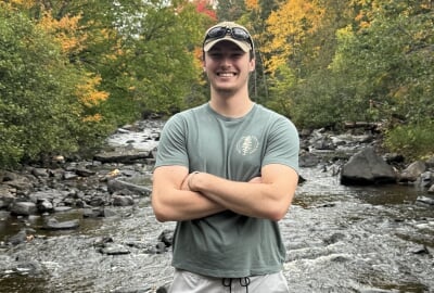 Daron Hebeler crossing a stream in a fall-colored forest.