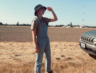 Allyson McQuiston stands in short, dry grass with an empty field behind her.