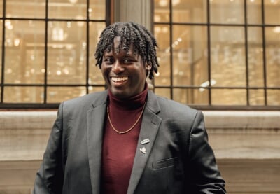 Elijah Joseph standing in front of a white stone building with large windows.