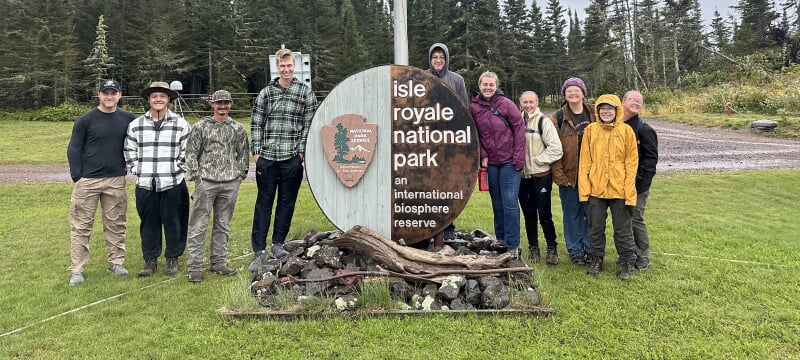 Students stand at the Isle Royale National Park welcome sign.