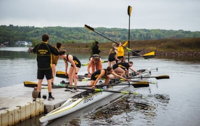 Eleven students on the dock preparing to get into the boat.