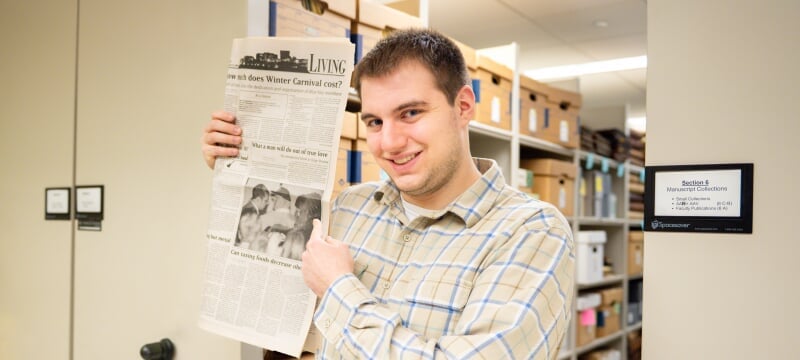 Ethan Rice holding a copy of the Lode from February 11, 2020, pointing to a story titled What a man will do out of true love: an unexpected show at Stage Revue.