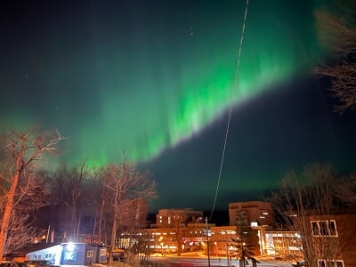 Northern lights stream from the sky over campus as seen from MacInnes Drive.