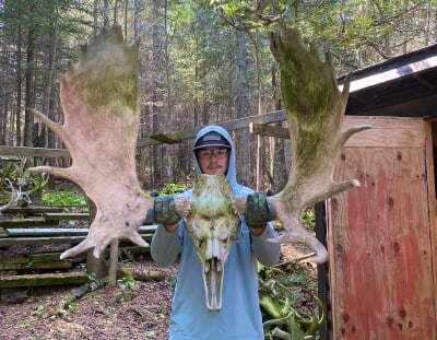 Jacob Sutter holds a large moose skull and antlers out toward the camera.