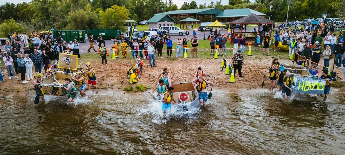 Students carrying their cardboard boats into the water as part of the annual homecoming festivities.