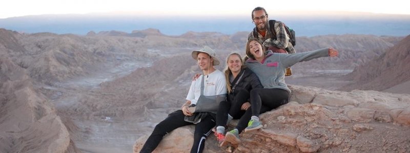 Students sitting on cliff in the desert