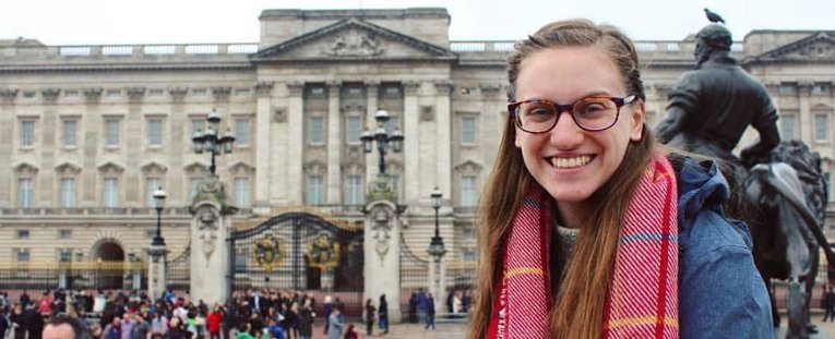 Study abroad student standing outside, in front of a large building