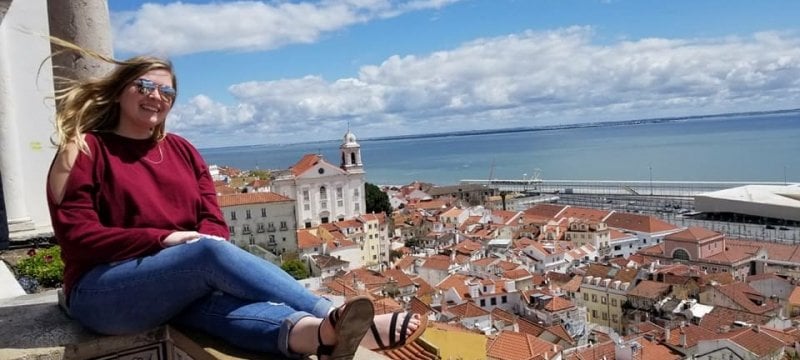 study abroad student sitting in front of European city