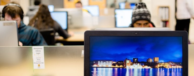 A computer workstation with students at more computers in the background.