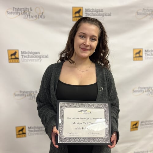 student pose with award for improved GPA