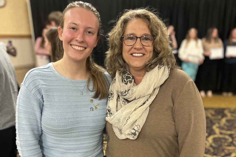 student poses with faculty