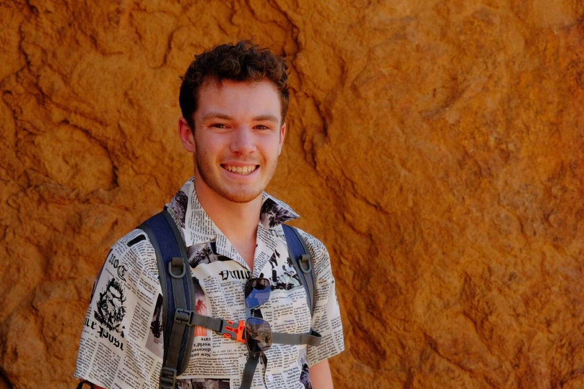 Student standing in front of a rock.