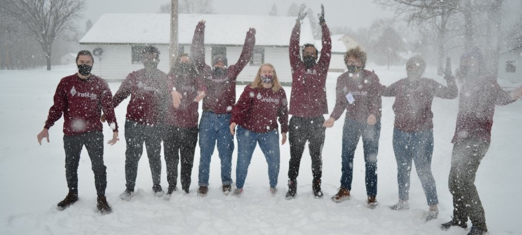 A family cluster plays in the snow outside.