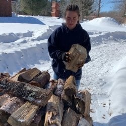 Riley Krause stacks wood at One Heartland
