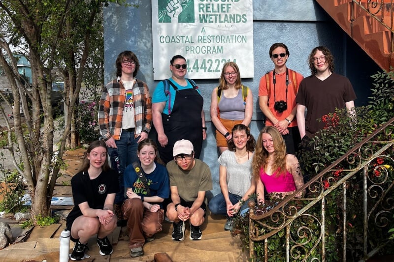  group posing for picture in front of a sign