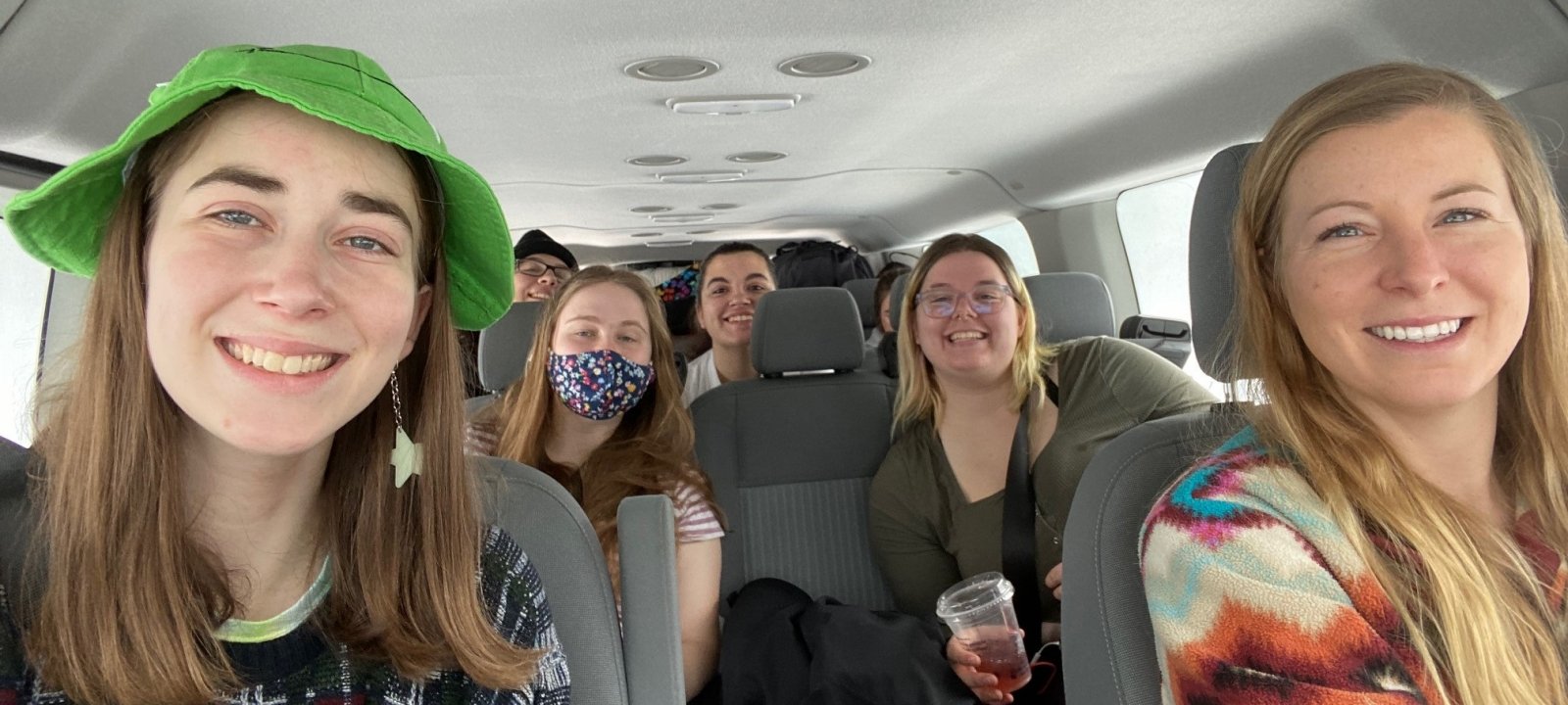 The group smiles as they ride in the van on the way to One Heartland