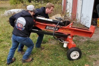 Volunteers move a log splitter indoors for winter