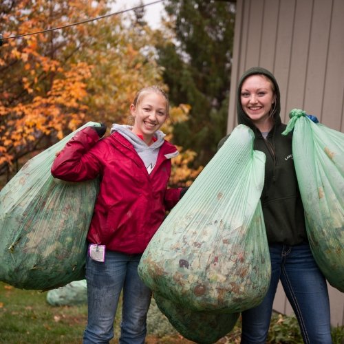 Two Michigan Tech students bagging leaves