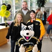 Father and two teens in a group photo with Blizzard T. Husky.