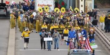 Blizzard T. Husky and the Michigan Tech Pep Band walking across the bridge in the parade.