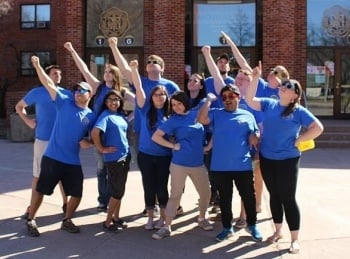 Students in blue shirts posing outside the Memorial Union.