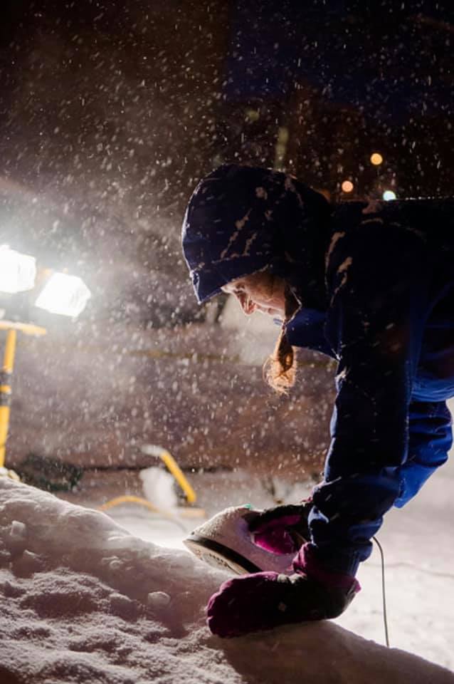 Night time picture of a student ironing snow while it snows