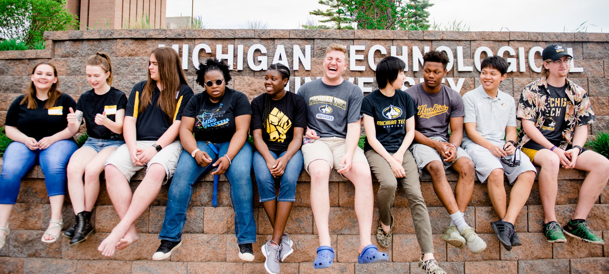A group of students sitting on a stone ledge at Michigan Tech.