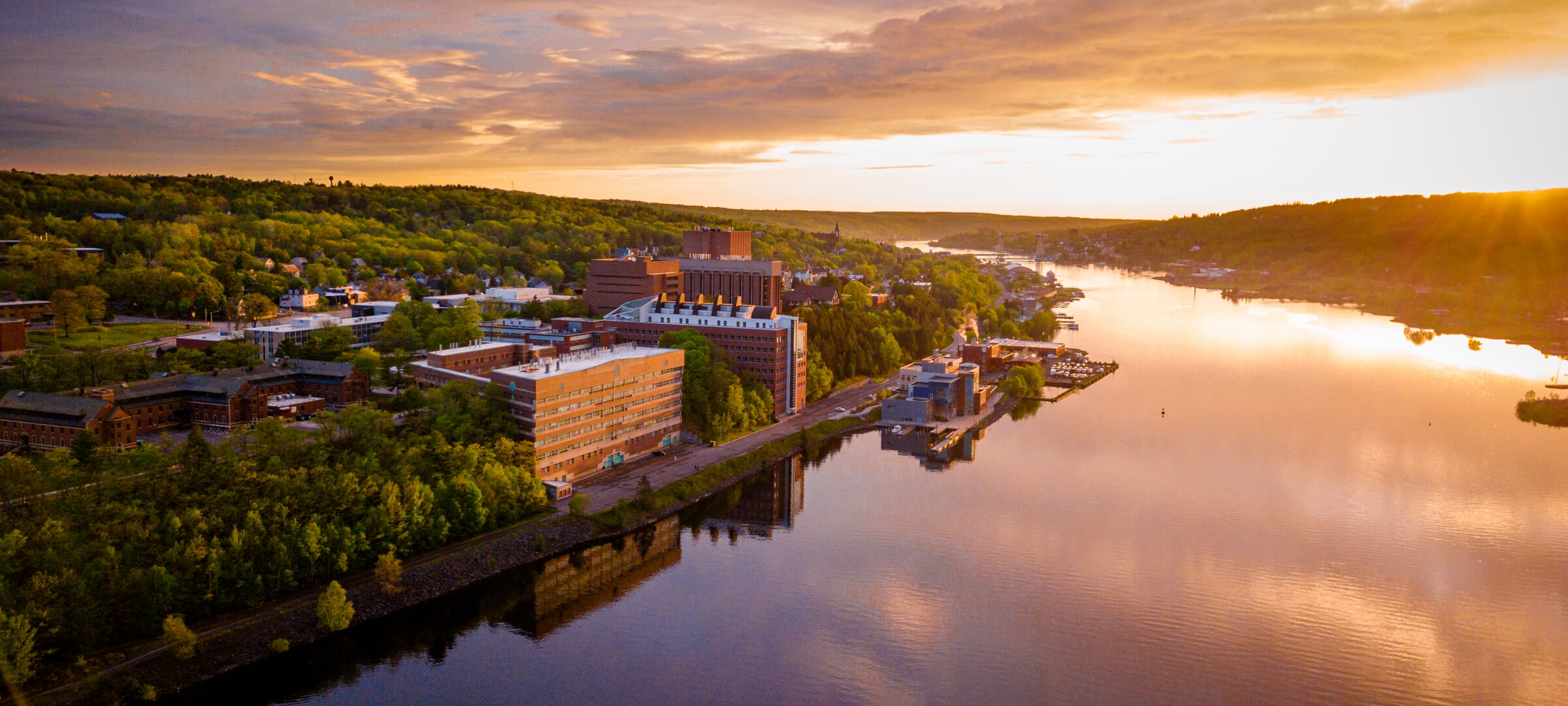 An aerial view of Michigan Tech's campus from across the Keweenaw Waterway at sunset.