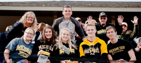 Families wave from the stands at a football game