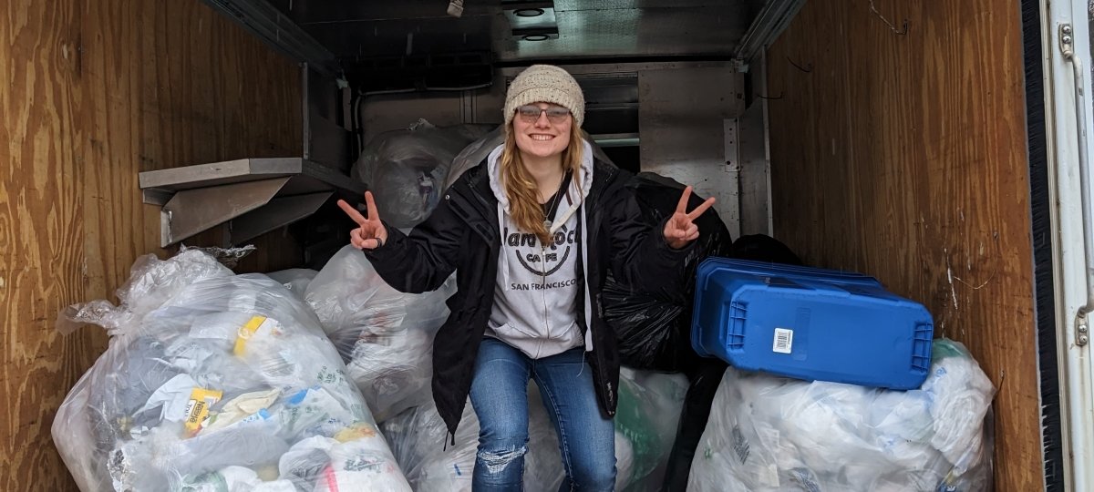 student standing in front of recycling