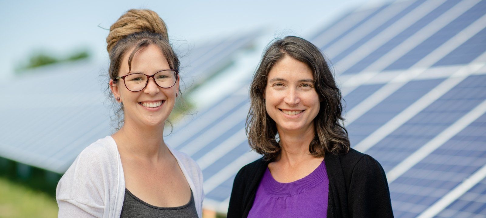 Two faculty standing in front of solar panels