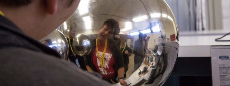 A student looks at his reflection in a metal orb.