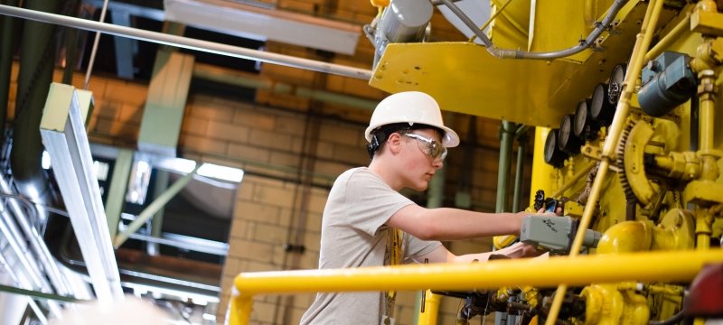 An SYP student works on a large machine.