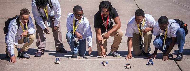 A group of boys race toy solar cars.